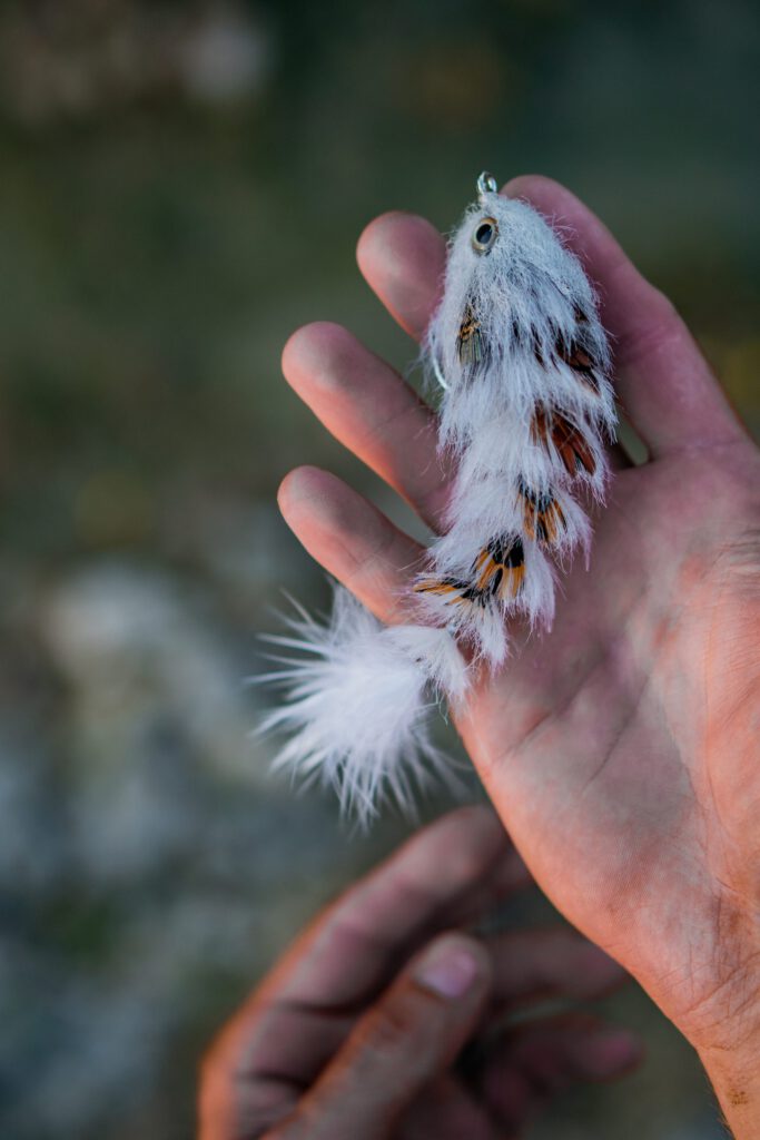 Hand holding a feather GameChanger fly at the bench